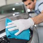 Ein hellblaues mikrofaser tuch wischt die glänzende schwarze oberfläche eines autos mit hygienorm safe fit weißen nitril handschuhen 200 stück