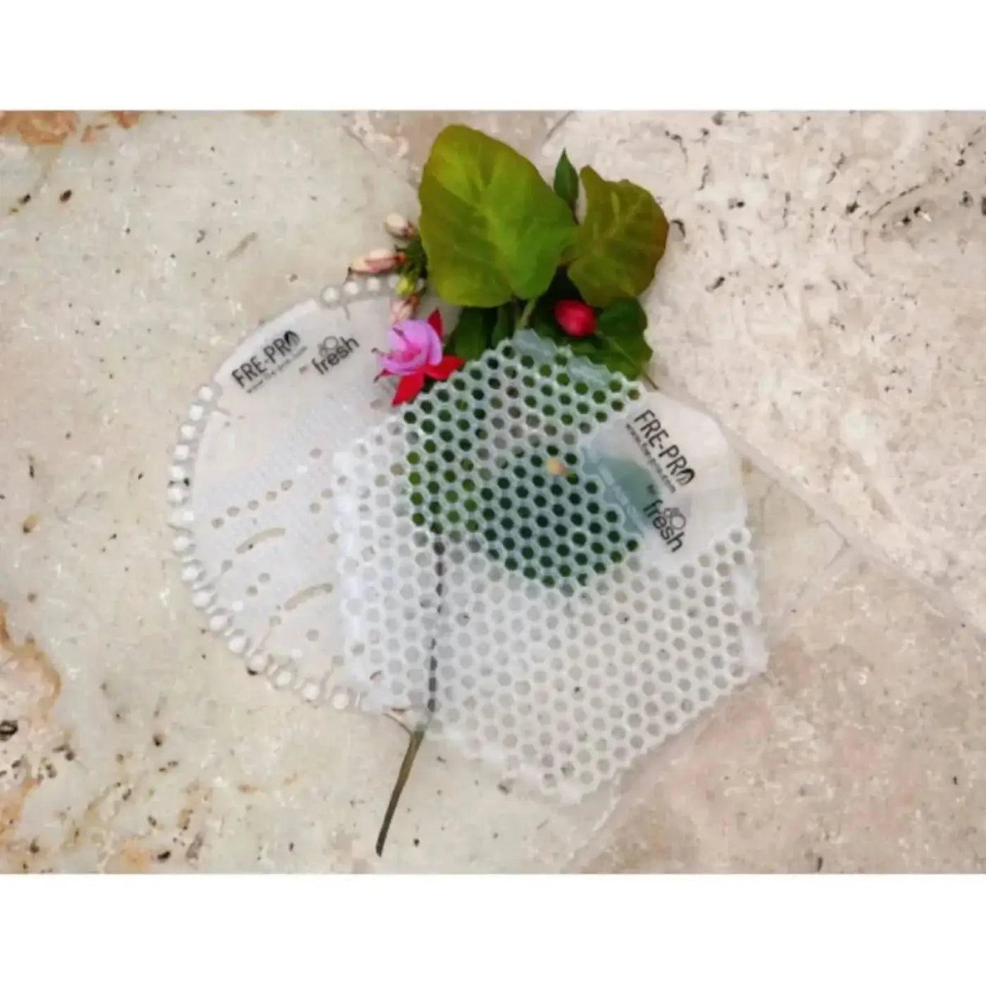 Weiße perforierte kunststoff-pflanzenanzuchttray frepro wave 2.0 mit grünen blättern und rosa blumen