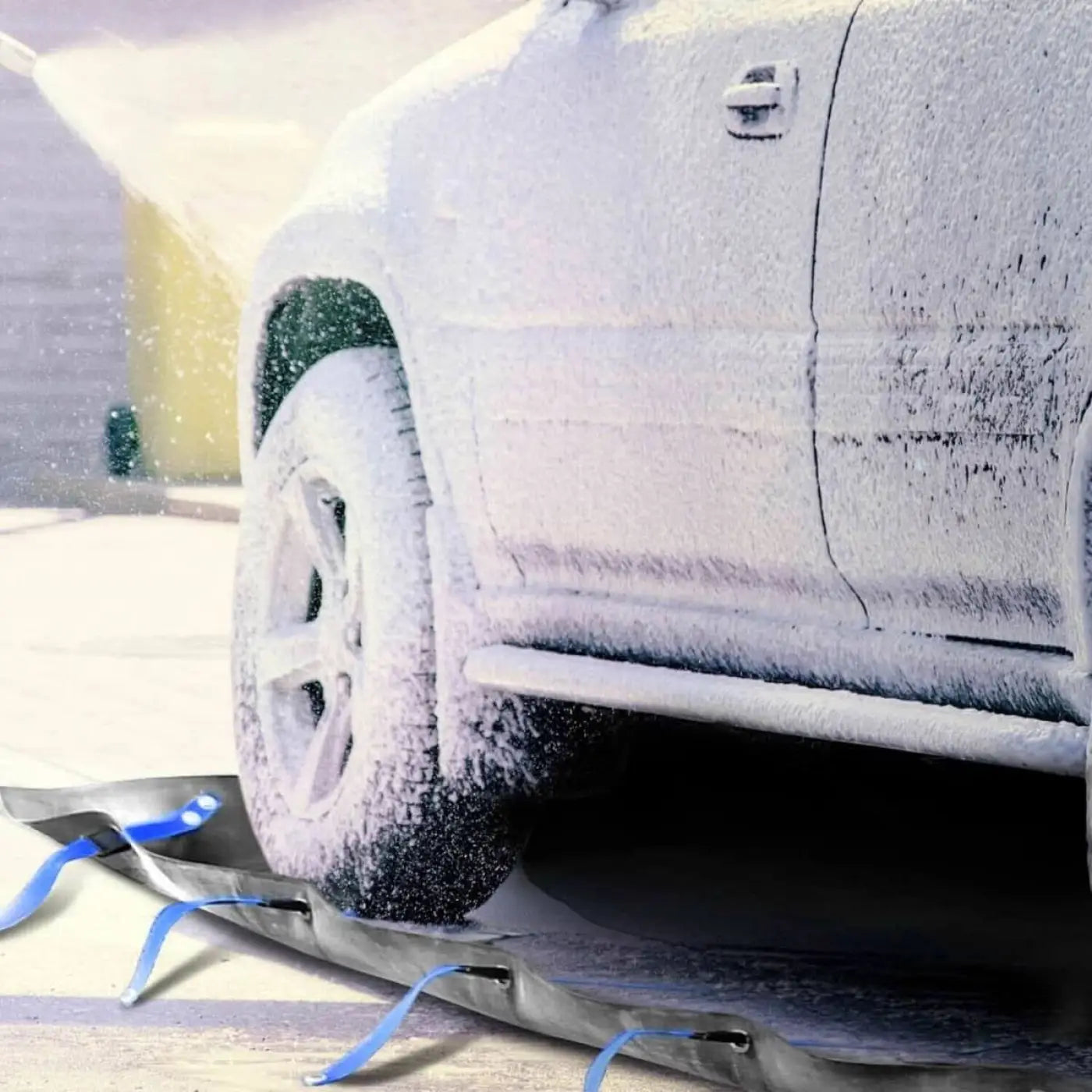 Schnee bedecktes suv-rad und seitenverkleidung auf schwarzem schneeschieber mit blauen riemen im bild zum hermes alkalistar-5 konzentrat 1 liter