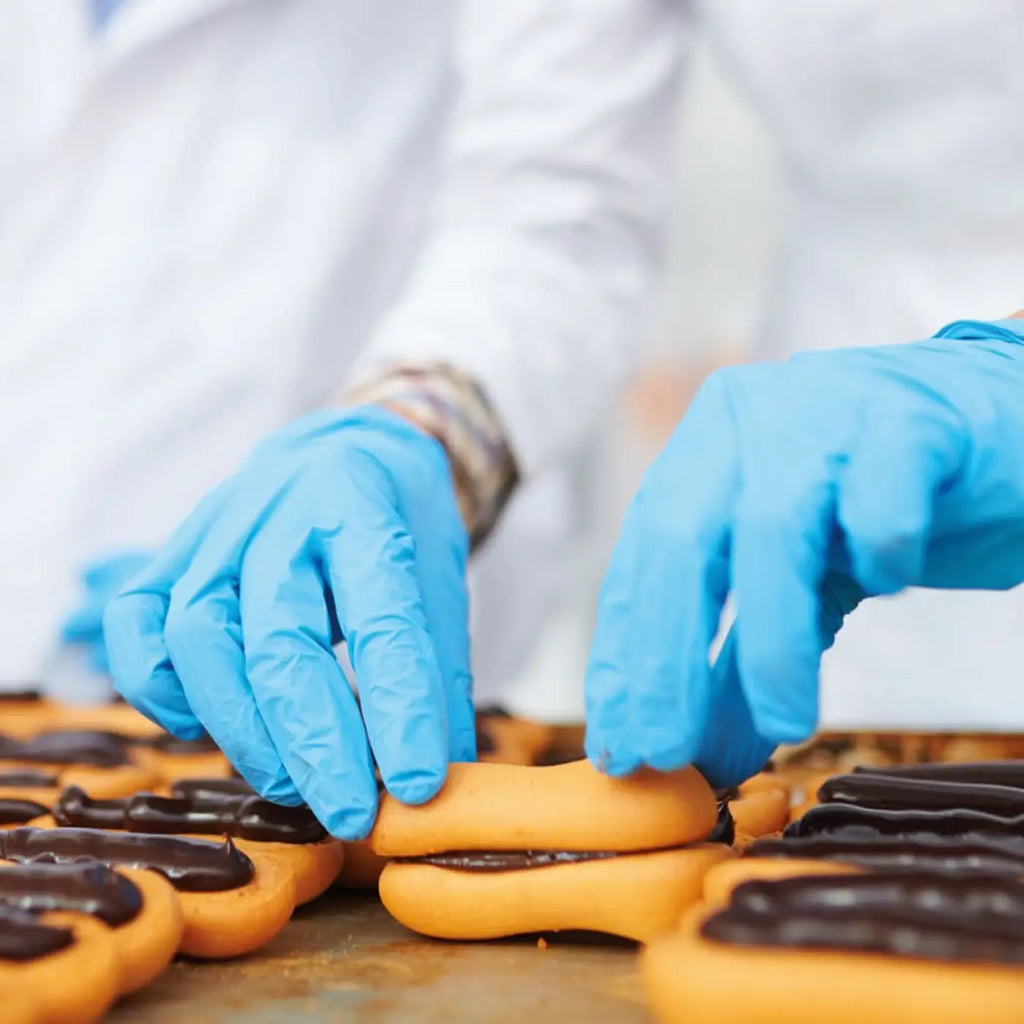 Blaue nitril handschuhe hygostar safe premium werden verwendet, um goldbraune schokoladen gefüllte backwaren zu handhaben