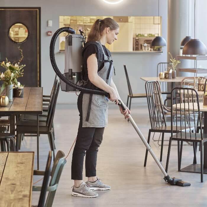 Grauer nilfisk gd5 back hepa basic rucksackstaubsauger mit schwarzem schlauch und griff von hinten gesehen