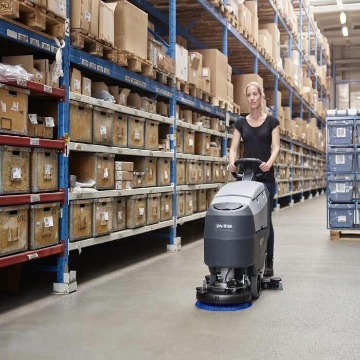 Graue und schwarze nilfisk scheuersaugmaschine sc401 b kombi mit blauem bürstenkopf für lagerbodenreinigung