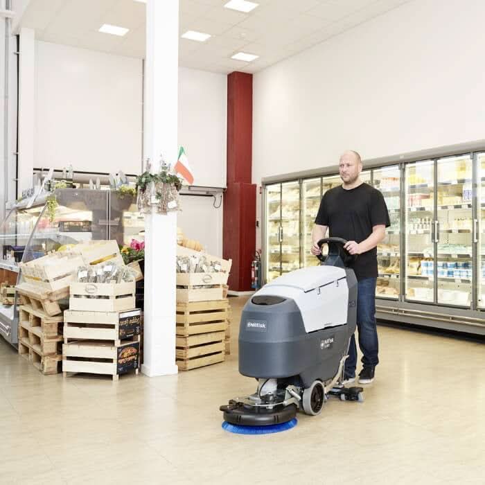 Grau weiße nilfisk scheuersaugmaschine sc401 b kombi mit blauem bürstenkopf für die industriebodenreinigung