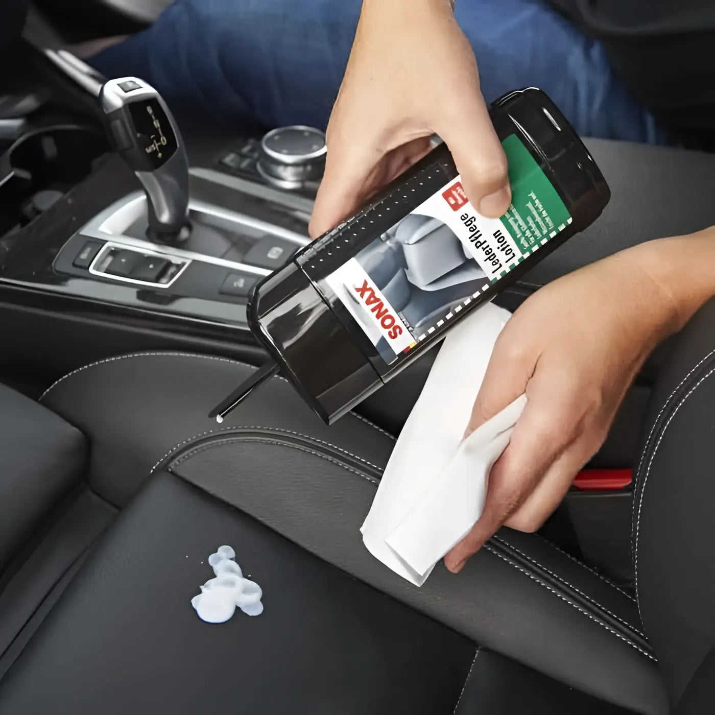 Schwarze sonax lederpflegelotion mit grün-weißem etikett wird zur reinigung eines autositzes verwendet