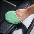 Grüner mikrofasermitt von sonax microfiberpflegepad zum reinigen einer schwarzen kunststoffoberfläche