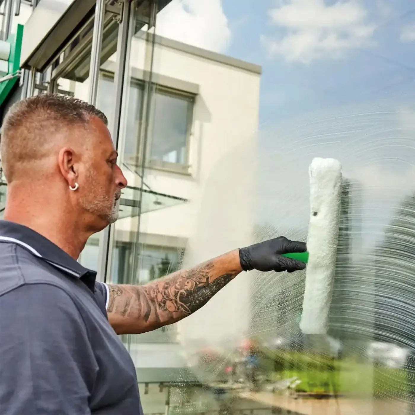 Weißer schaum bedeckter fensterreinigungssqueegee mit grünem griff ungger stripwasher unitec träger oe