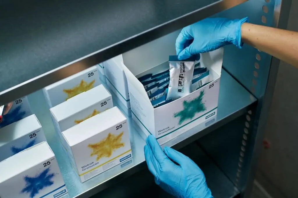 Eine blau-weiße verpackung von wetex granulam in einer box mit grünem sternmuster für sanitärreiniger sticks